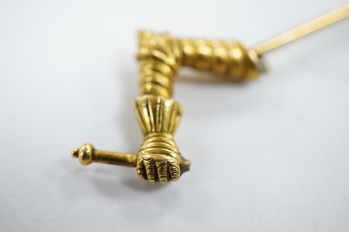 A yellow metal stick pin, the terminal modelled as a Knight's arm holding a scroll(a.f.), 79mm, together with two pairs of yellow metal and gem set ear clips including 9ct and opal doublet.